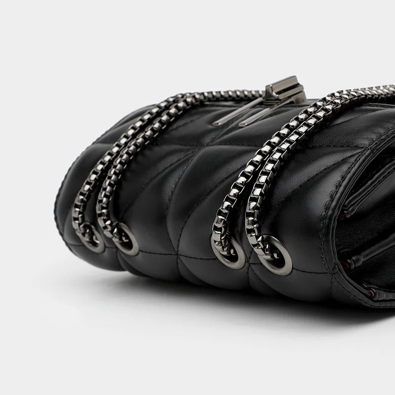 Close-up of a black quilted leather handbag with silver chain straps.