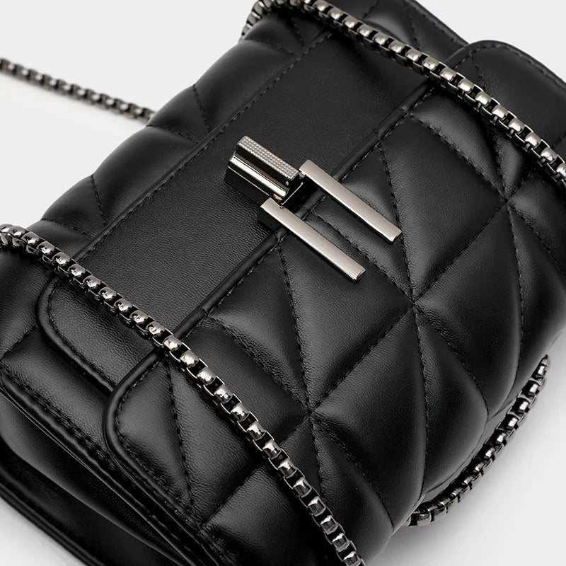 Close-up of a black quilted leather handbag with a silver chain strap.