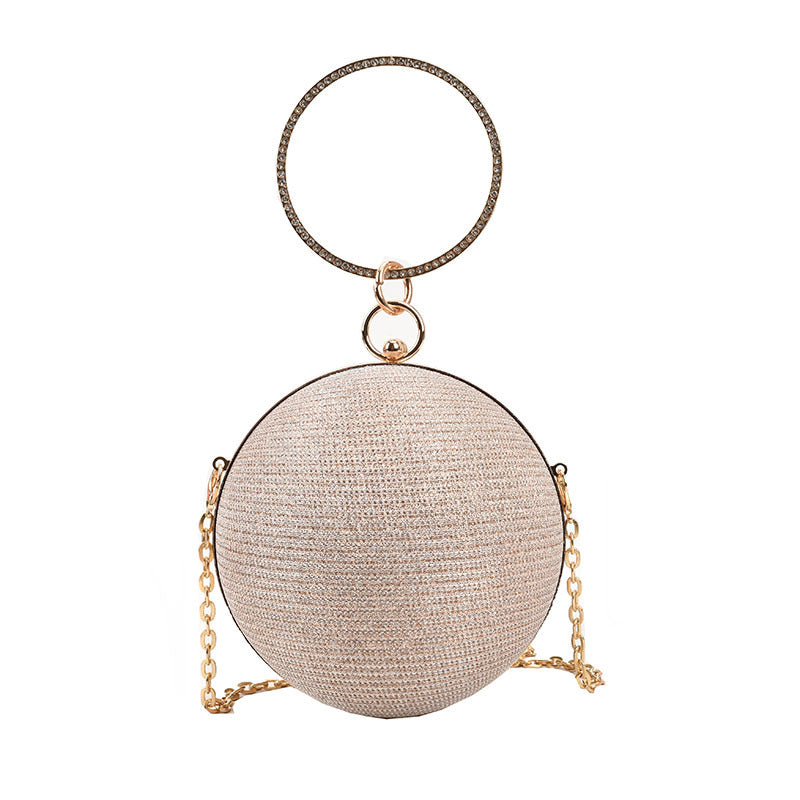 Elegant beige spherical clutch with a large crystal-embellished gold ring handle.
