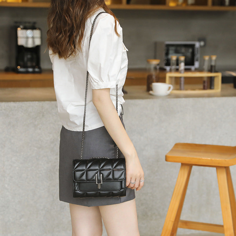 Black quilted leather cross-body handbag with a silver chain strap and clasp.