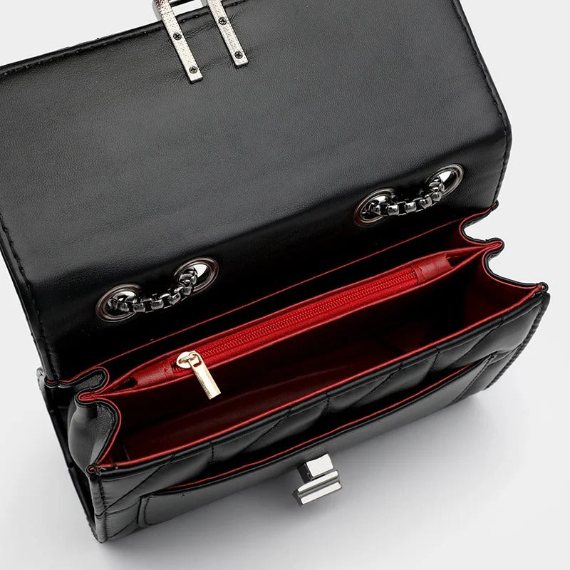 Open black quilted leather handbag with red interior and silver chain straps.